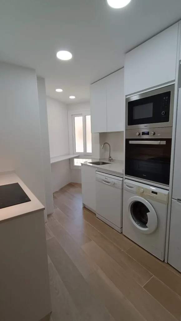 Cocina blanca con columna de horno y lavadora integrada