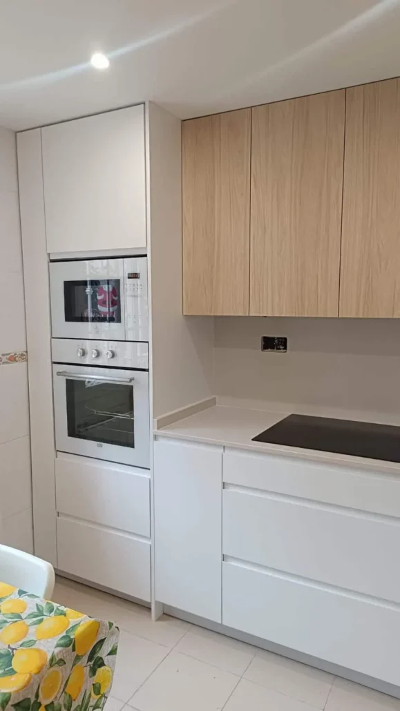 Cocina blanca con horno y microondas en columna y encimera de madera