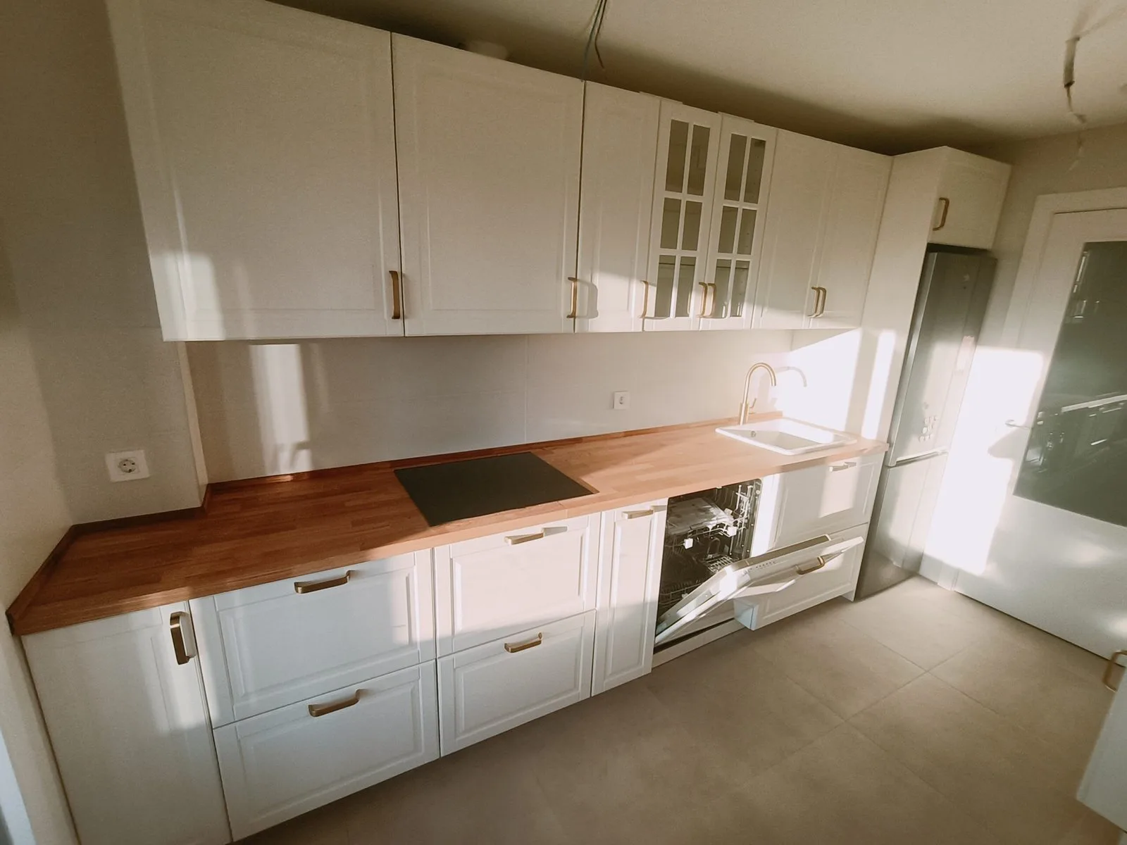 Cocina blanca de estilo clásico con encimera de madera y placa negra