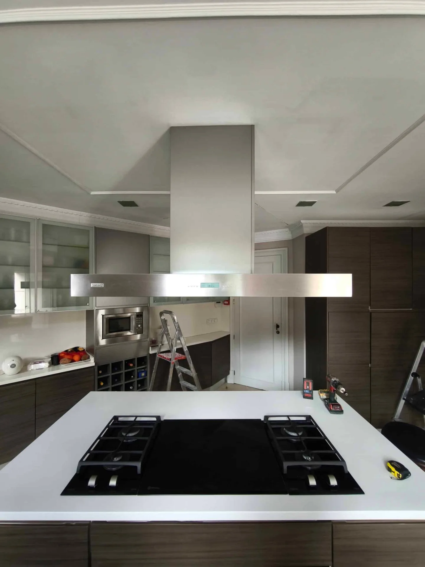 Cocina blanca con isla, placa de inducción y campana de acero en Madrid
