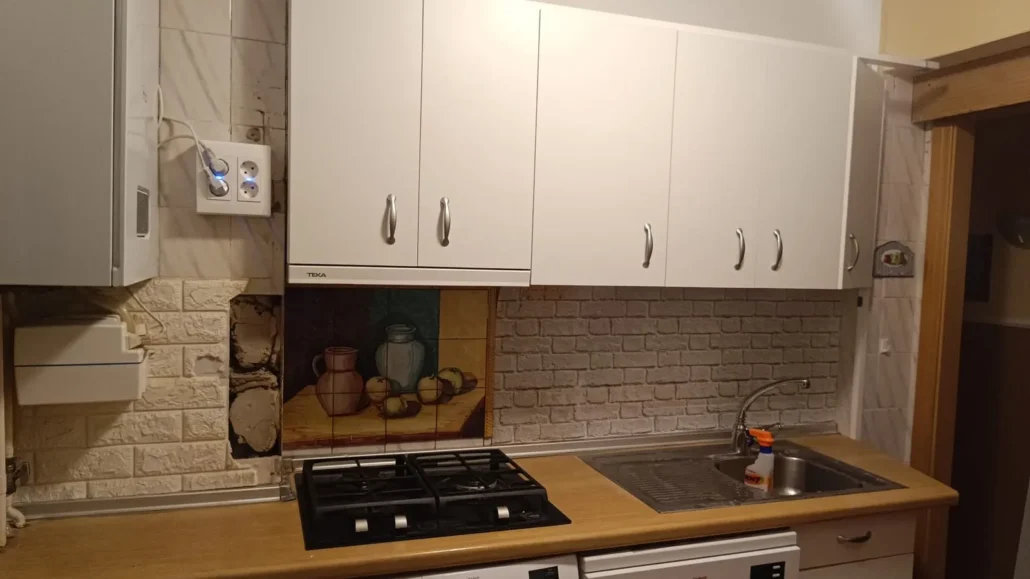 Cocina blanca con encimera de madera y salpicadero de ladrillo visto