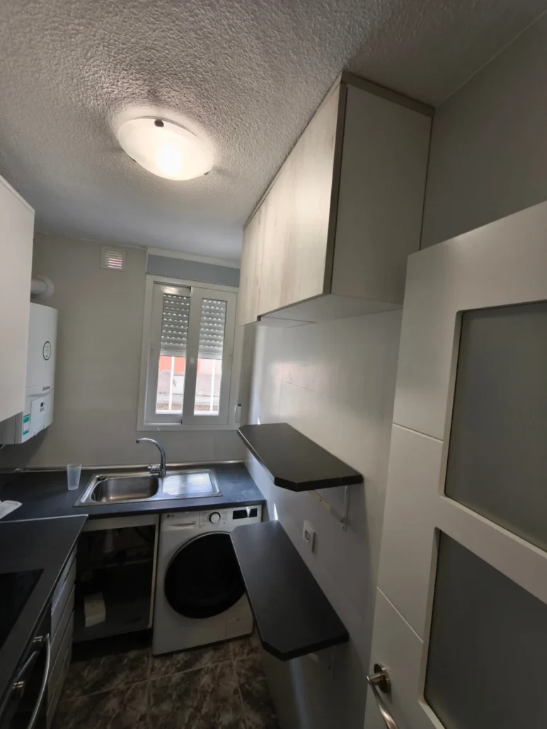 Cocina compacta con muebles grises y lavadora integrada