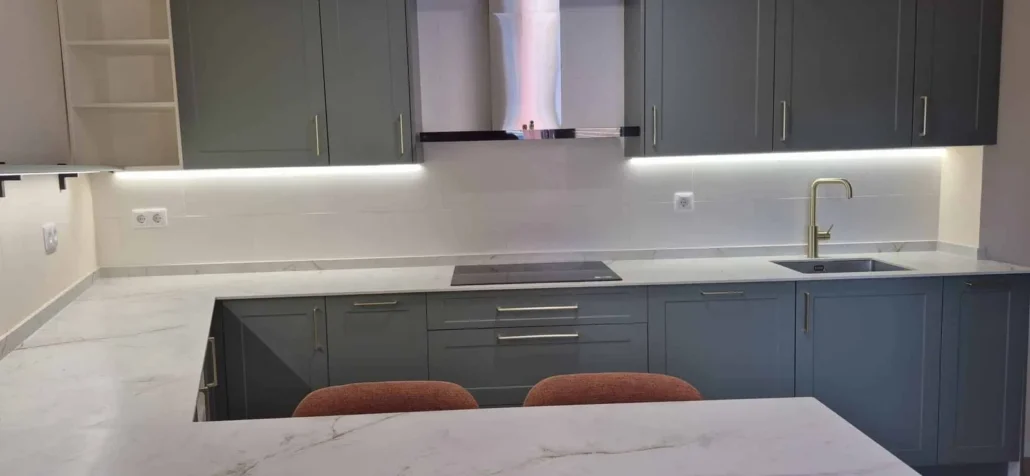 Cocina gris y blanca con isla de cuarzo y taburetes naranjas en Madrid