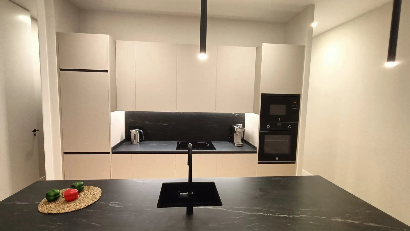 Cocina moderna oscura con isla minimalista y placa negra en Madrid