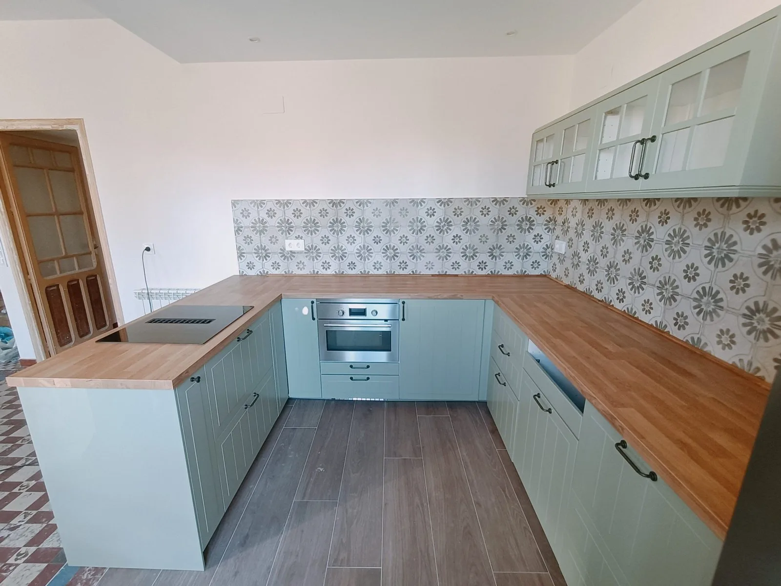 Cocina verde en U con encimera de madera y azulejos decorados