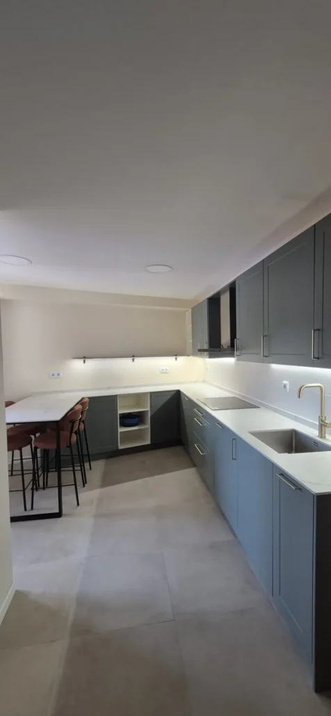 Isla de cocina con encimera clara, muebles grises y taburetes